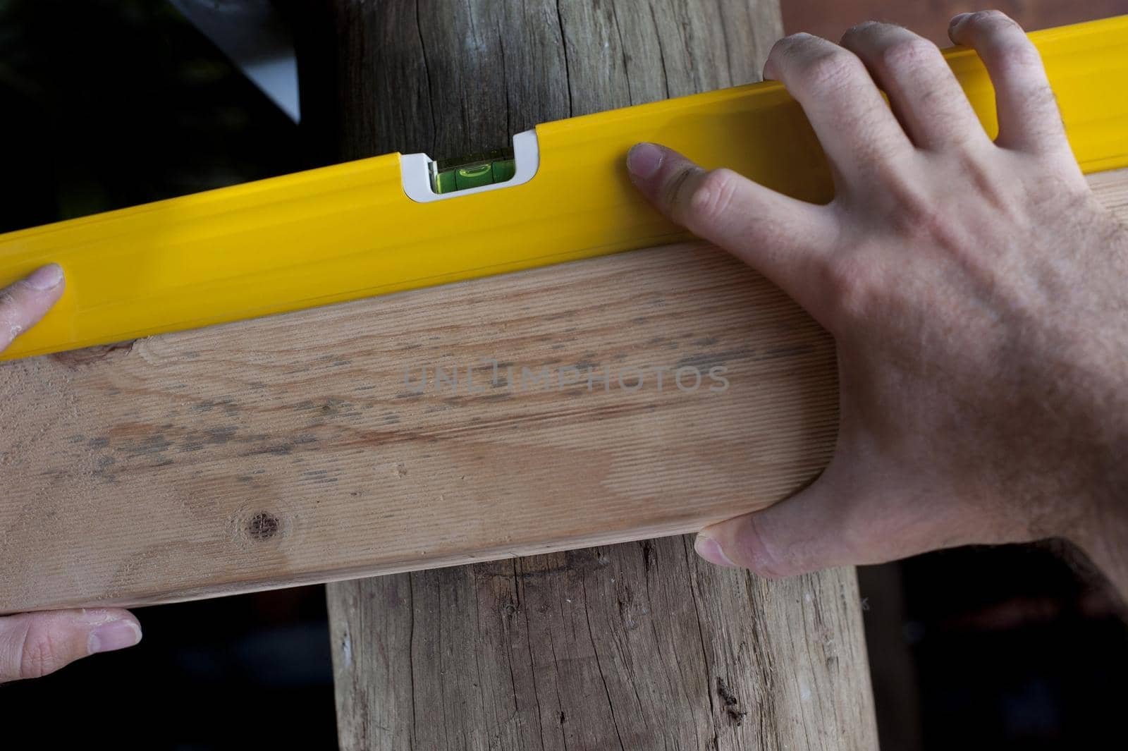 Carpenter using a spirit level to adjust the horizontal angle on a plank of wood, close up of his hand and the bubble in the level
