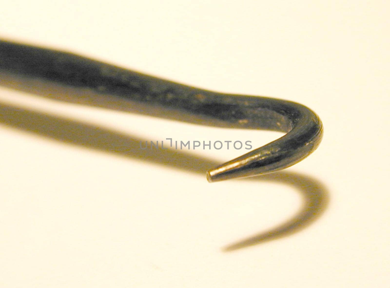 Metallic hook scraper, useful tool for soldering, close-up with shadow and copy space on beige
