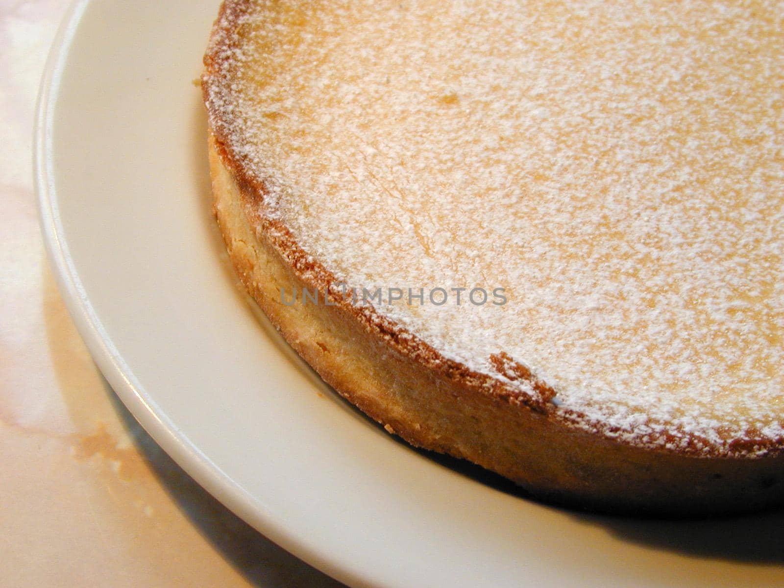 Freshly baked golden crispy pastry pie crust sprinkled with icing sugar served on a plate in a close up culinary or baking background