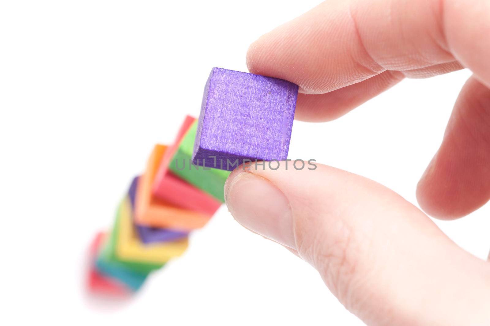 Hand building a tower of colourful wooden toy blocks conceptual of growth and development through learning and education