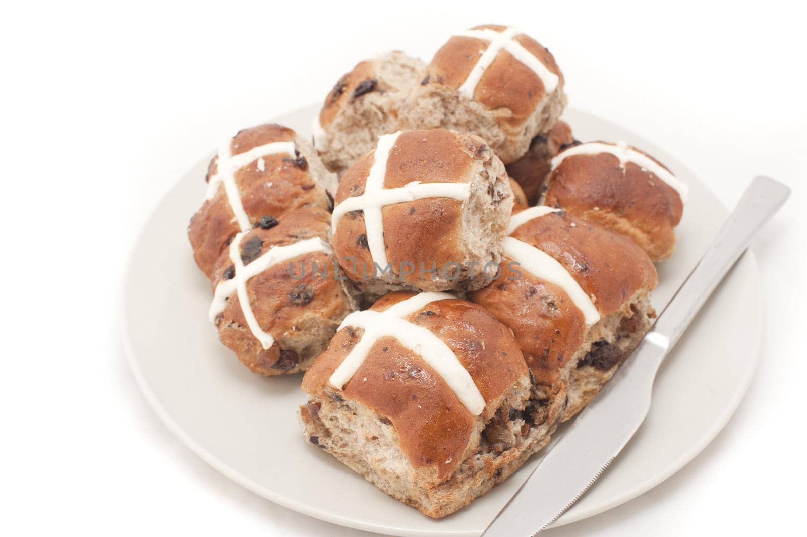 Plate of freshly baked spicy fruity Hot Cross Buns with raisins symbolic of the crucifixion of Christ at Easter