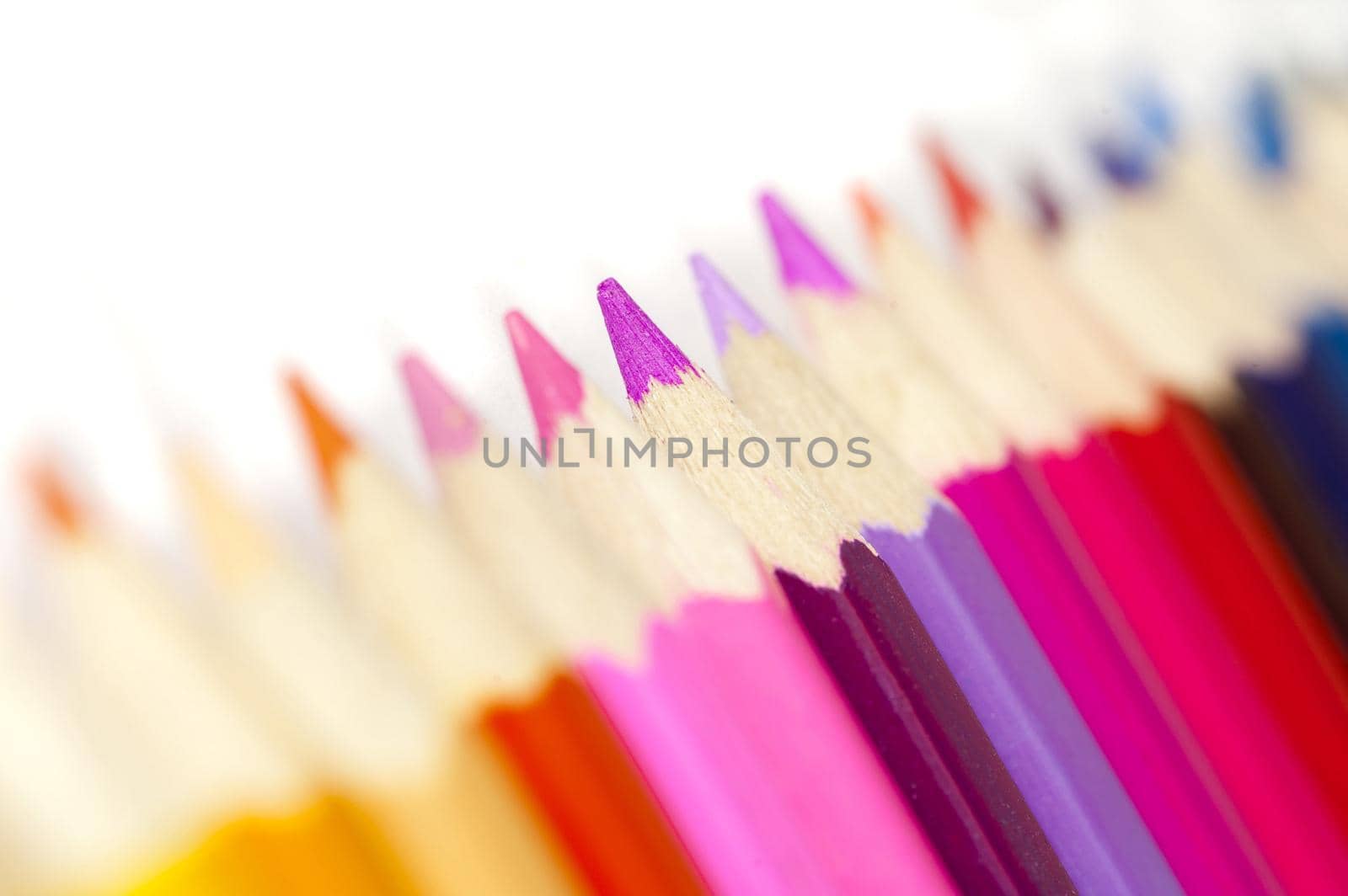 Extreme macro selective focus close up view on warm tones of colored pencils over white background