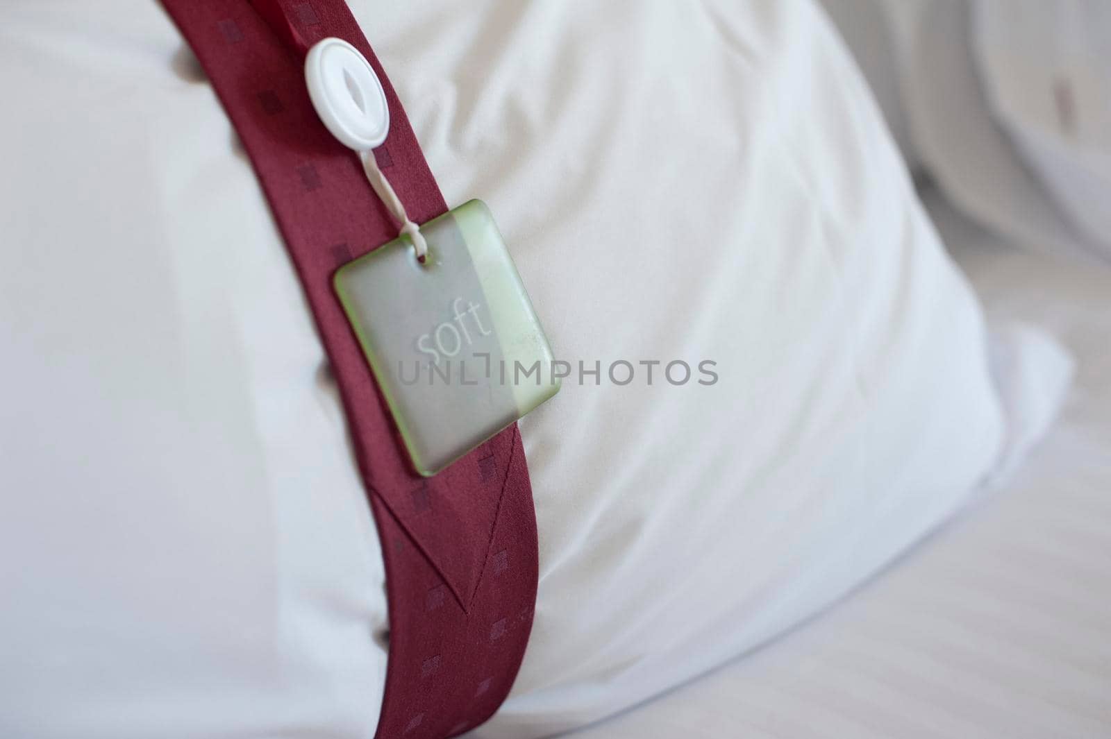 Hotel bedroom pillow with a decorative band tied around it with an attached tag, close up view conceptual of the hospitality industry