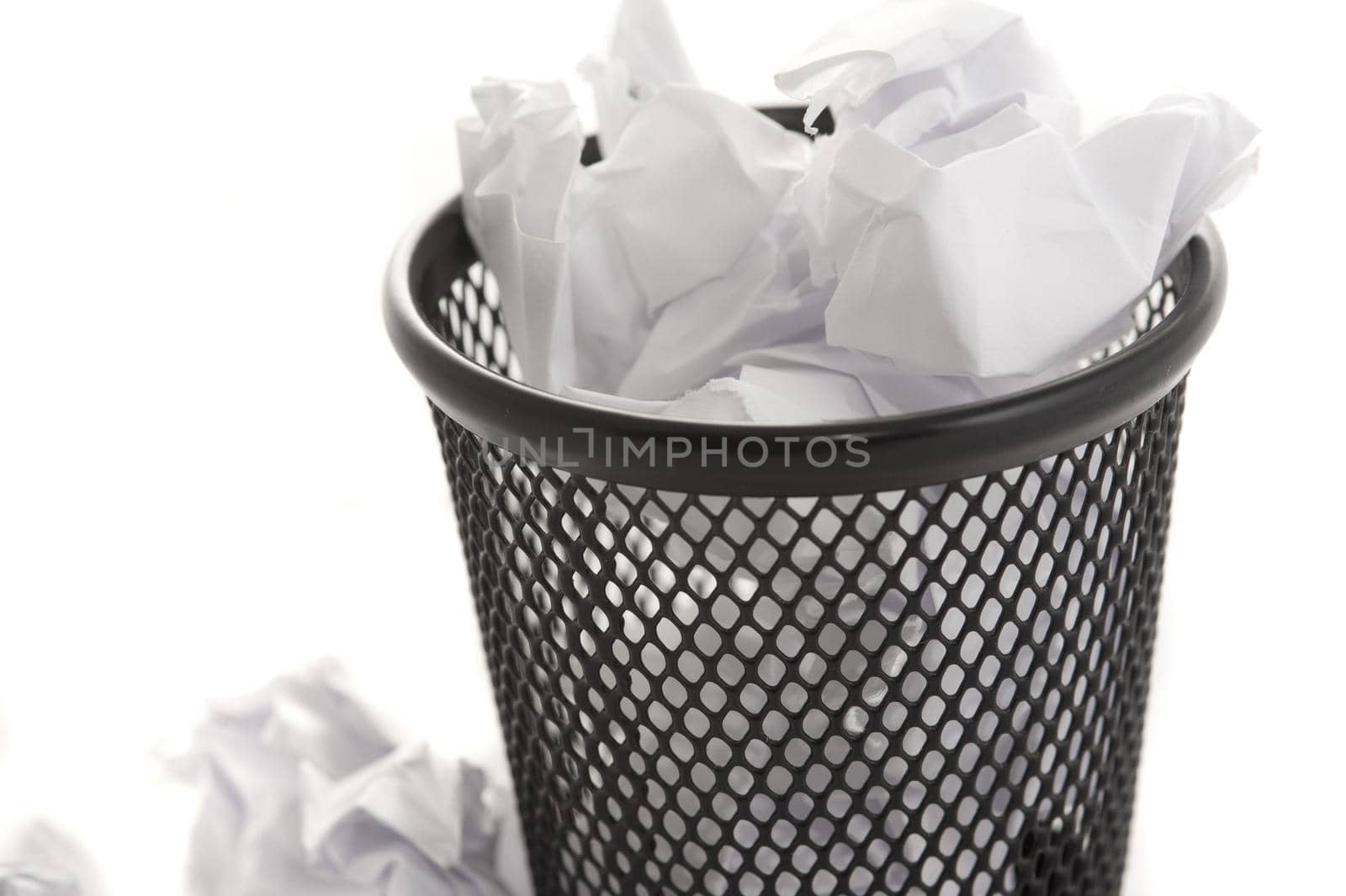 Wastepaper bin filled to overflowing with crumpled white paper