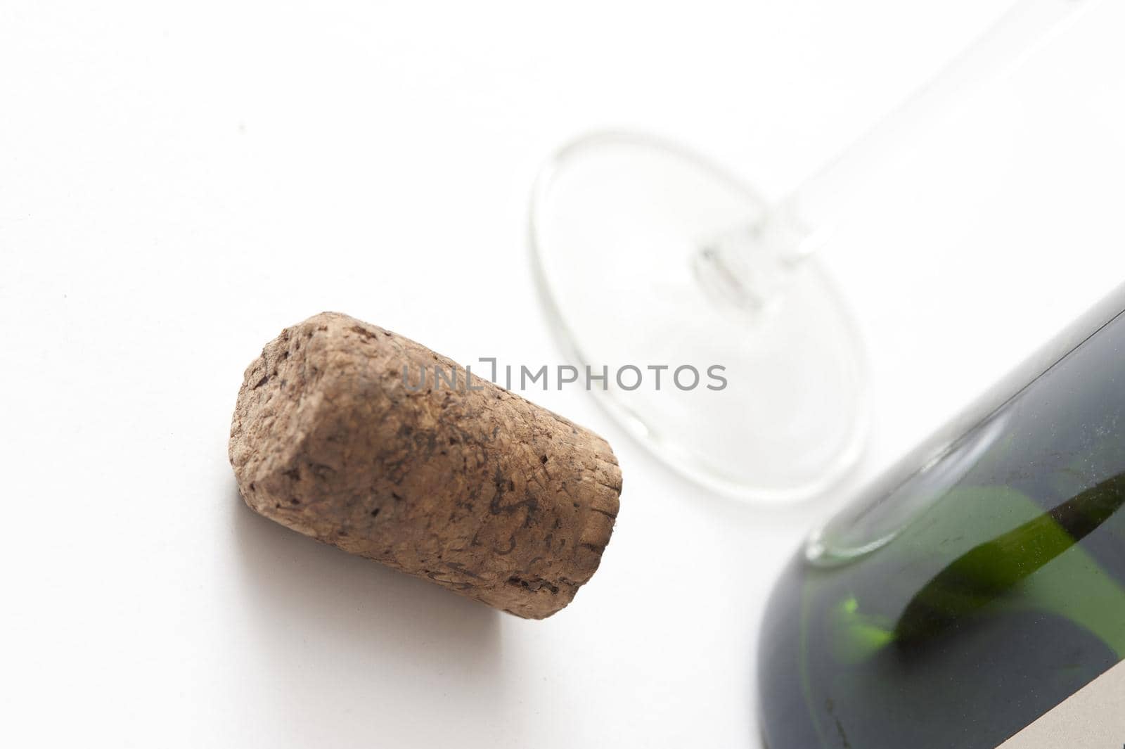 Close Up of Cork Beside Wine Bottle and Glass on White Background in Studio
