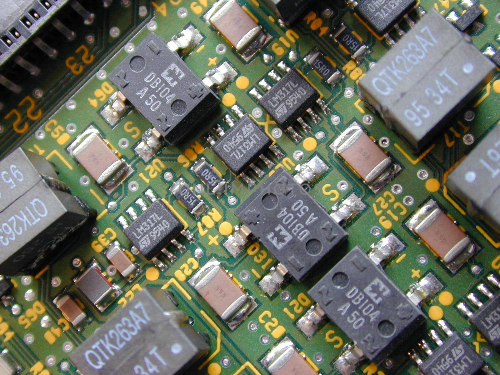 Close up of diode rectification, transformer and transistor electrical components on a green circuit board.