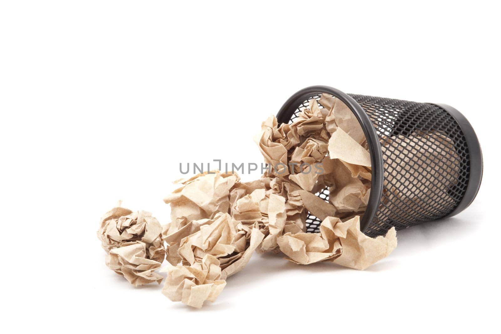 Wastepaper bin lying on its side with crumpled discarded paper spilling out onto floor