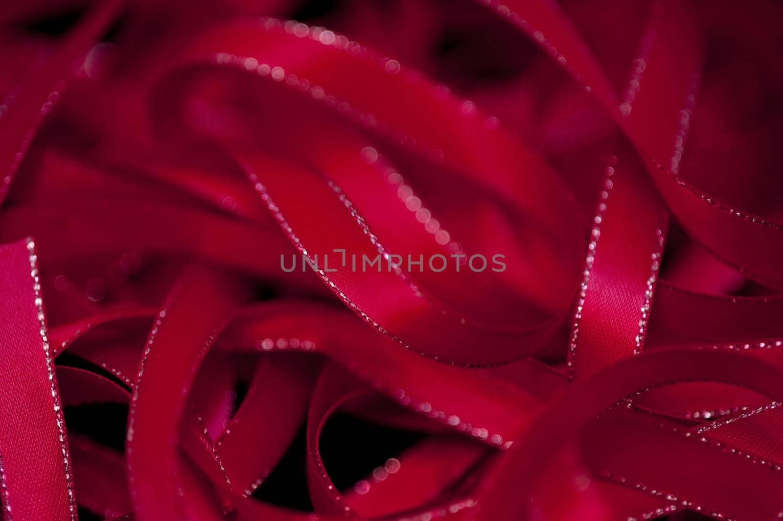 Full frame background of twisted red ribbons with little gold trim on sides with copy space