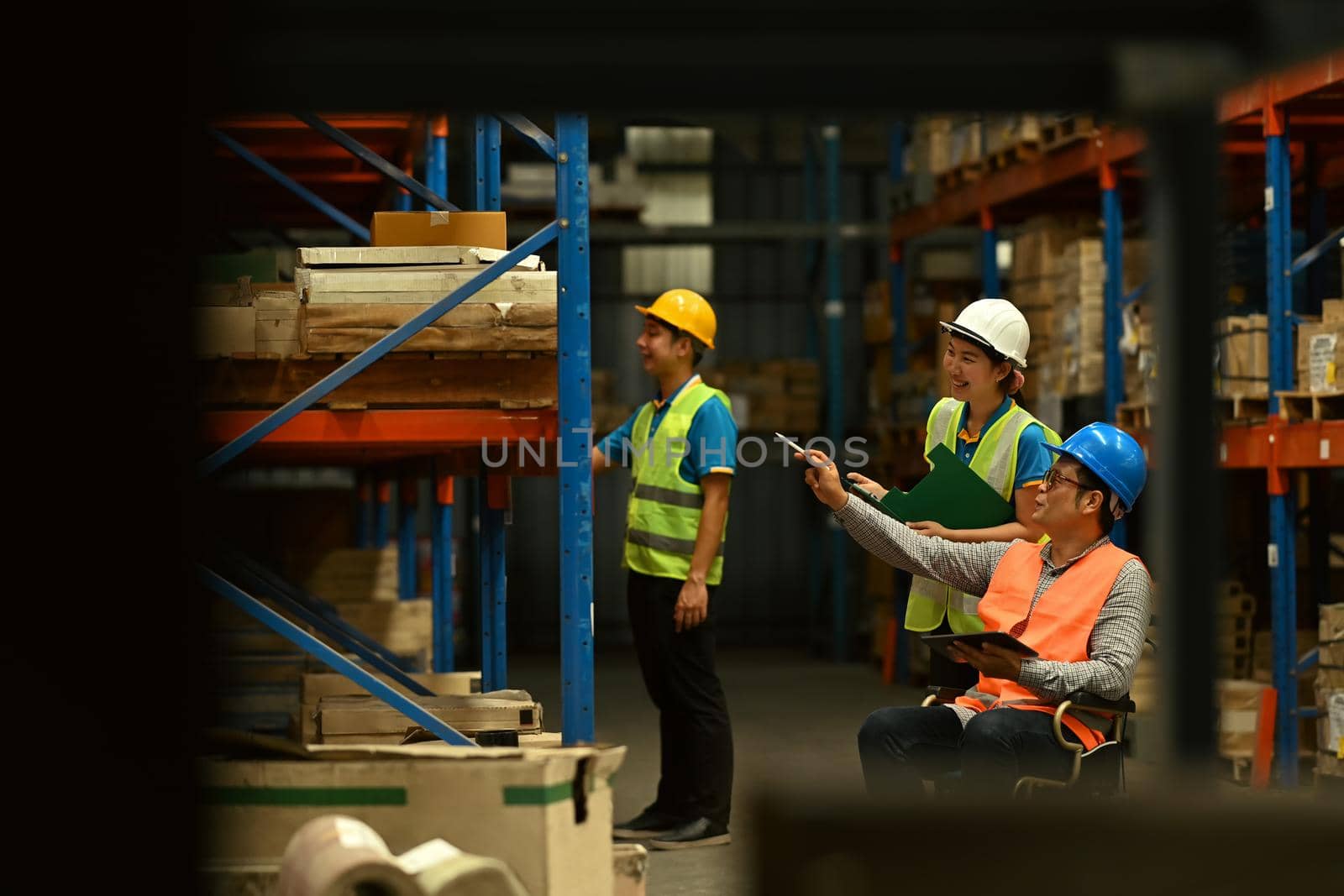 Storehouse employees workers in hardhats and and vests working together in warehouse. Logistics, and manufacture storehouse occupation concept by prathanchorruangsak