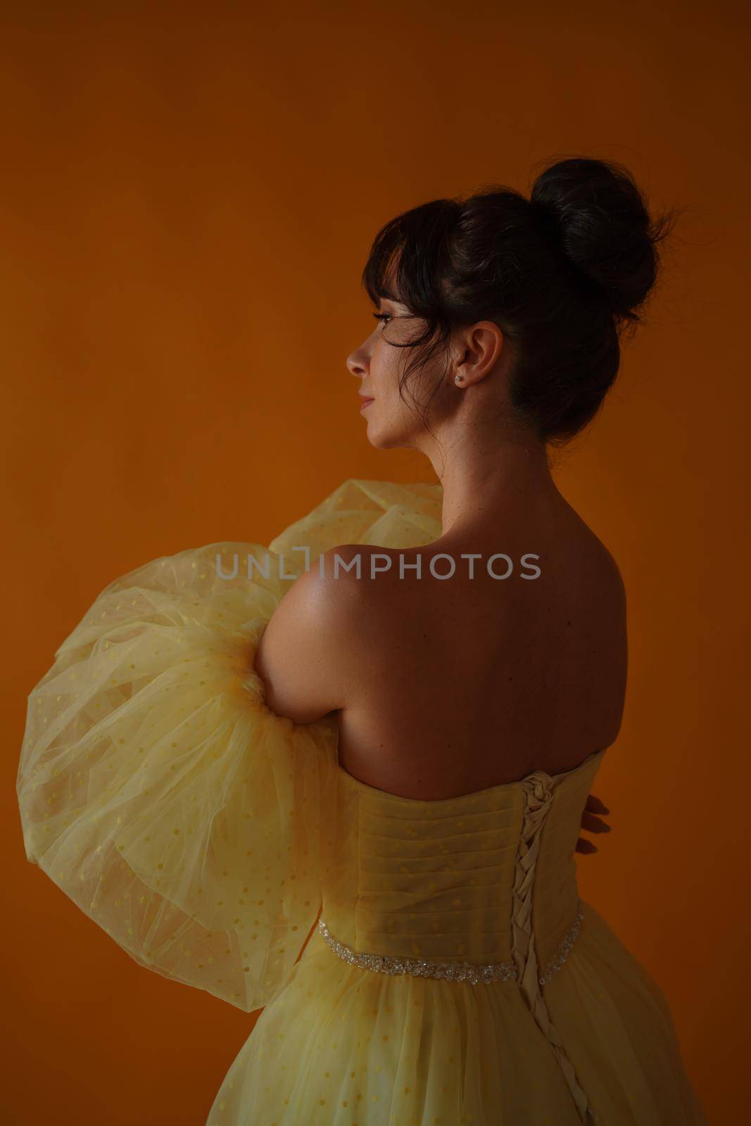 Profile portrait of a beautiful middle-aged woman in a yellow dress, her hair pulled up against a yellow background by Matiunina