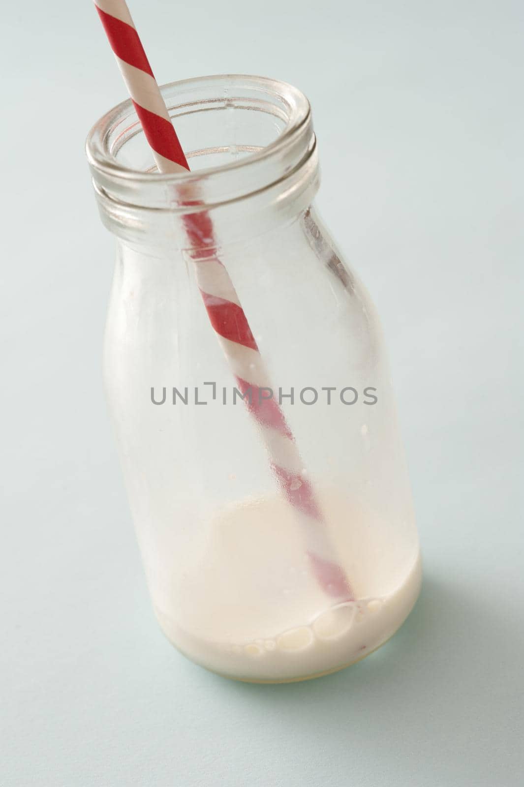 Remnants of milk in a glass bottle with straw after the contents have been drunk or consumed in a healthy diet concept