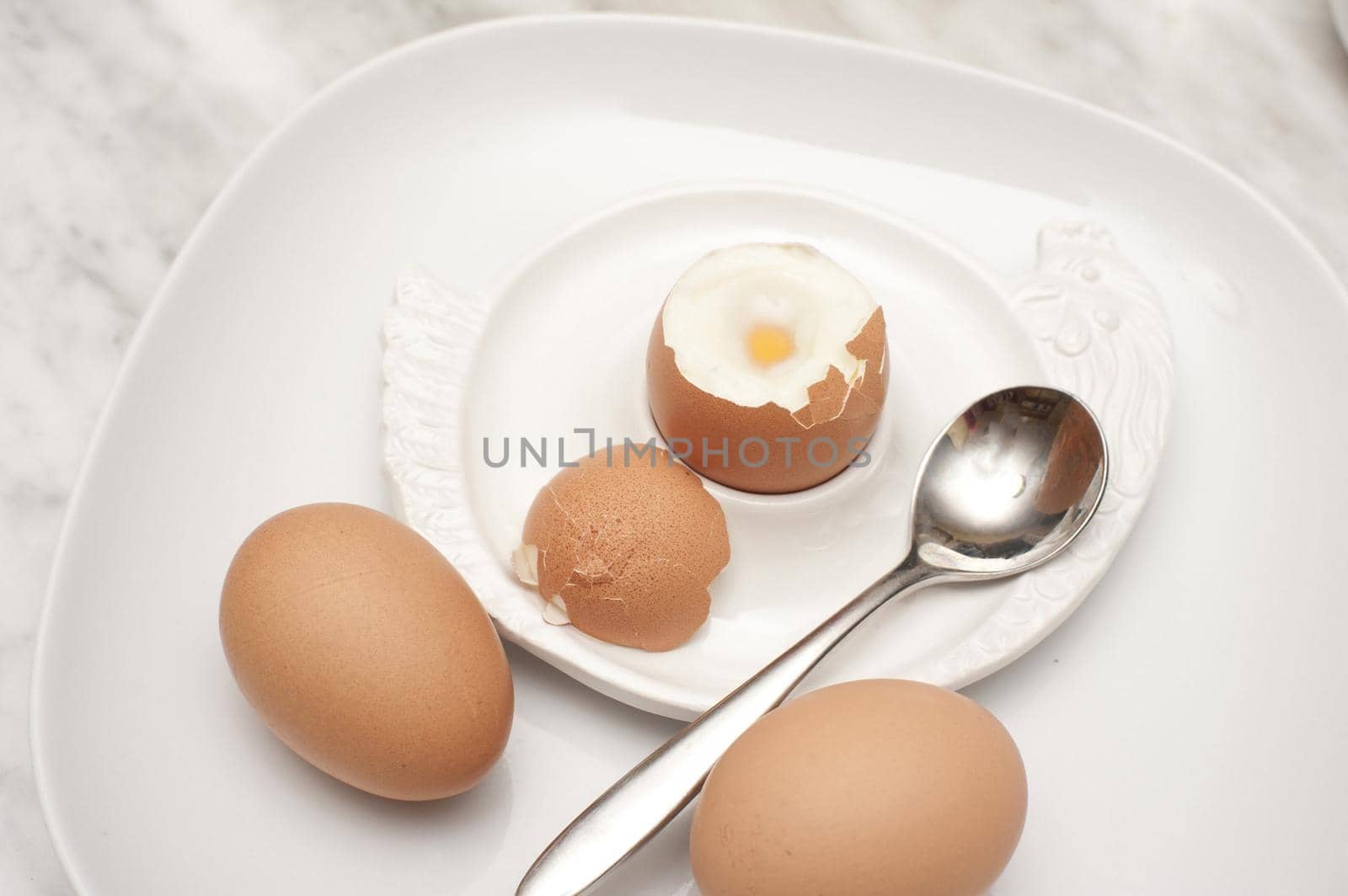 Boiled eggs for breakfast with a soft boiled egg in an egg cup served with two additional eggs on the side