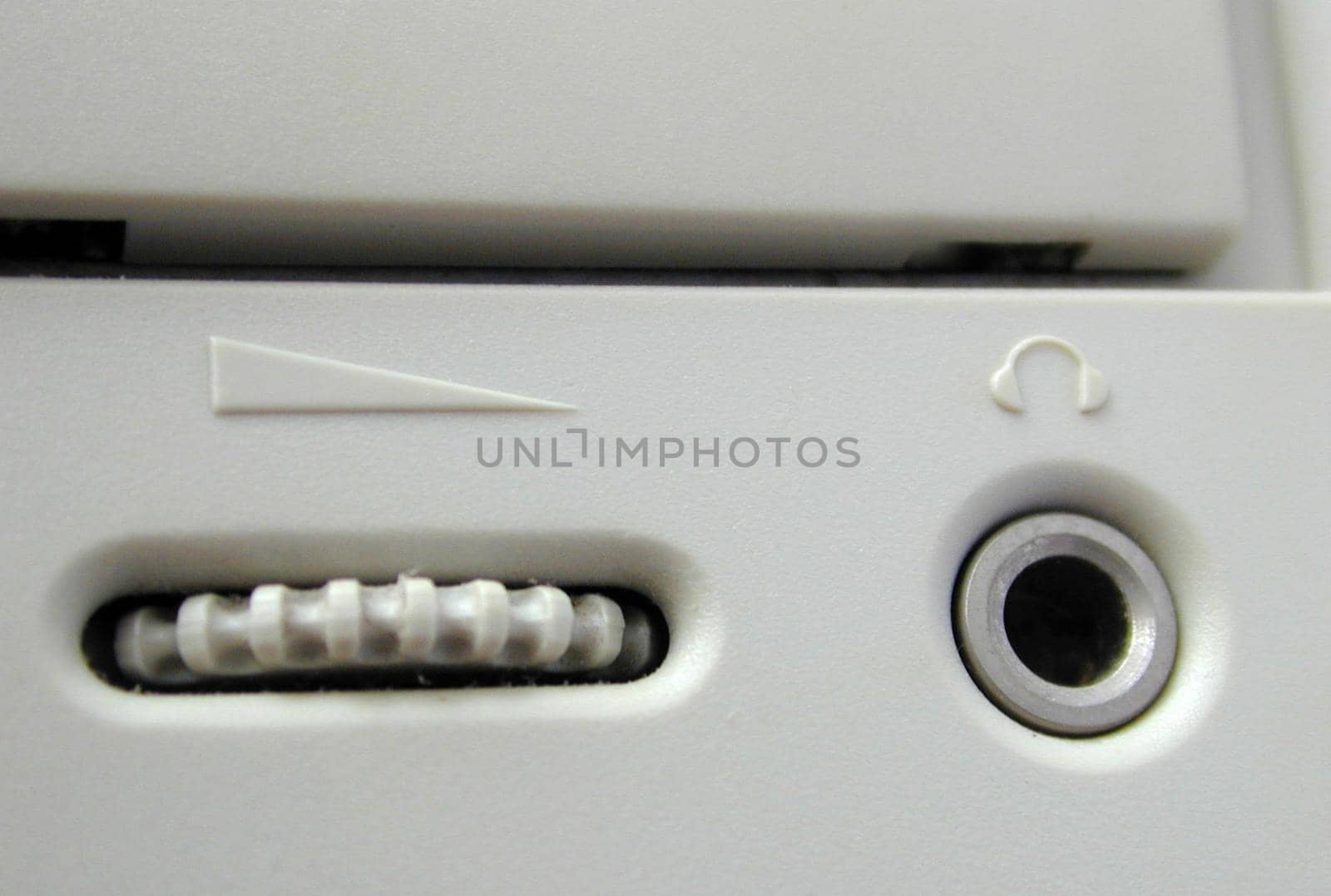 Close up detail of a ridged CD ROM volume control knob on a white machine in a technology, data storage and entertainment concept