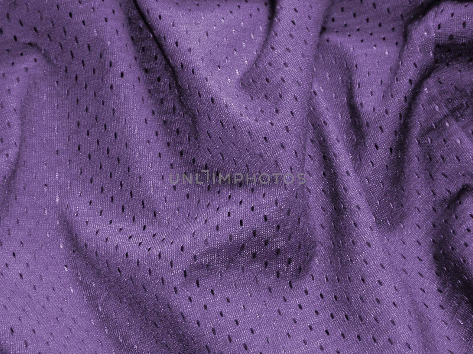 Soft luxurious folded purple fabric with a sateen pattern of darker dots in a full frame decor background