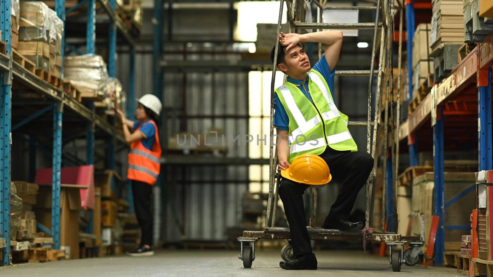 Storehouse employees workers in hardhats and and vests working together in warehouse. Logistics, and manufacture storehouse occupation concept by prathanchorruangsak