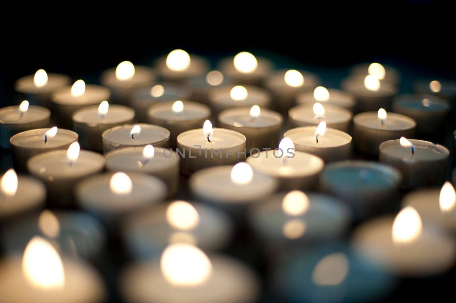 Seasonal background with an array of burning Christmas candles with festive twinkling flames on a black background with shallow dof