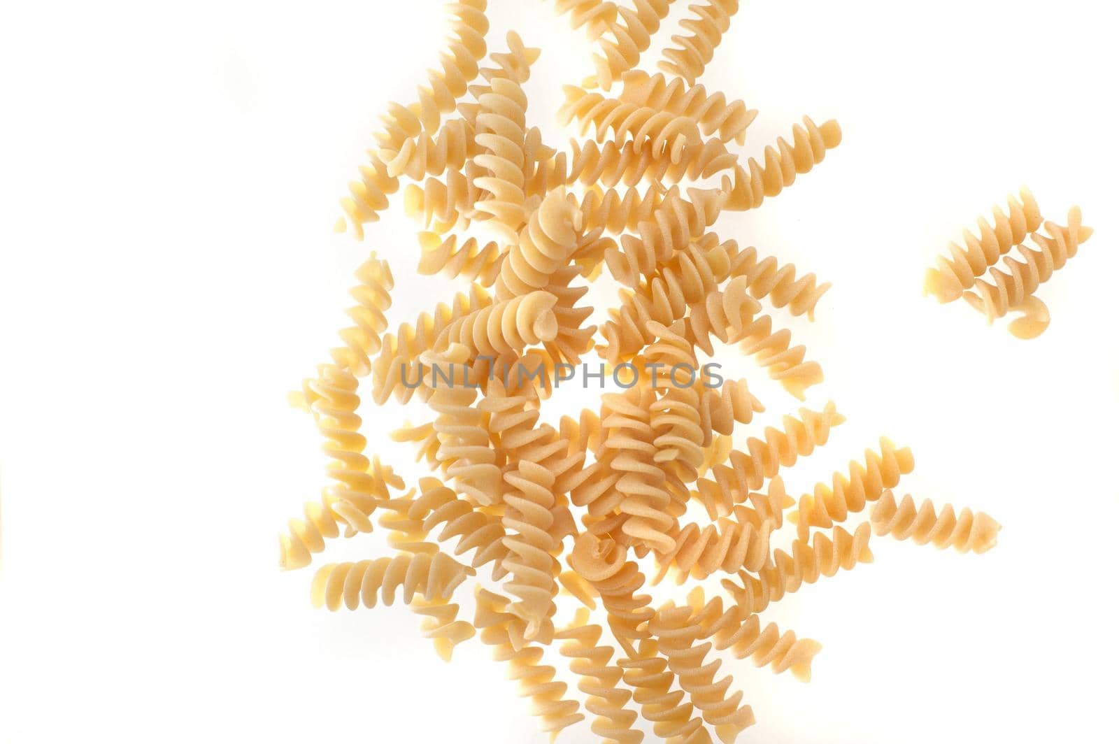 Spiral twist uncooked dried Italian pasta scattered on a white background with copyspace viewed from above