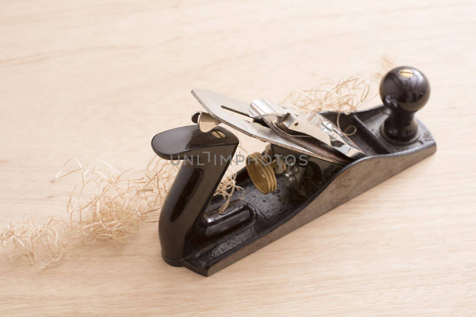 Old-fashion woodworking carpenters plane tool in close-up with wooden shavings on table surface