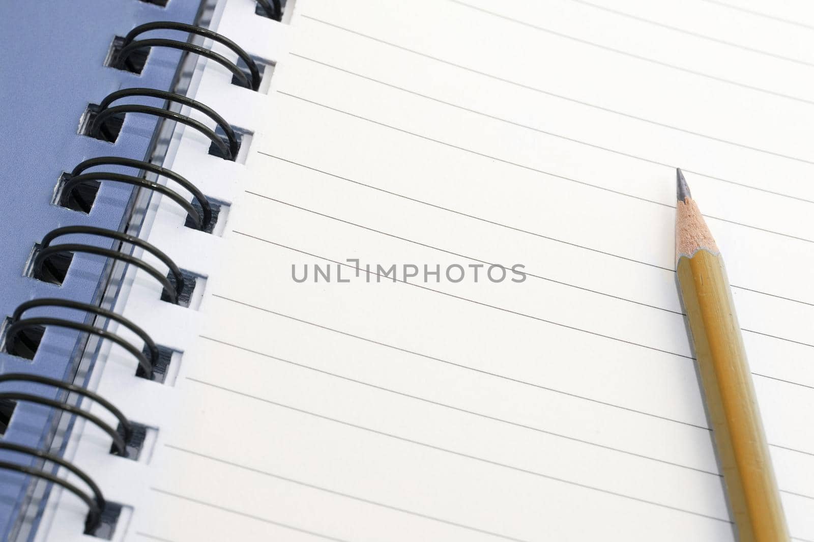 Pencil lying on a blank lined spiral bound notebook with copyspace for your text