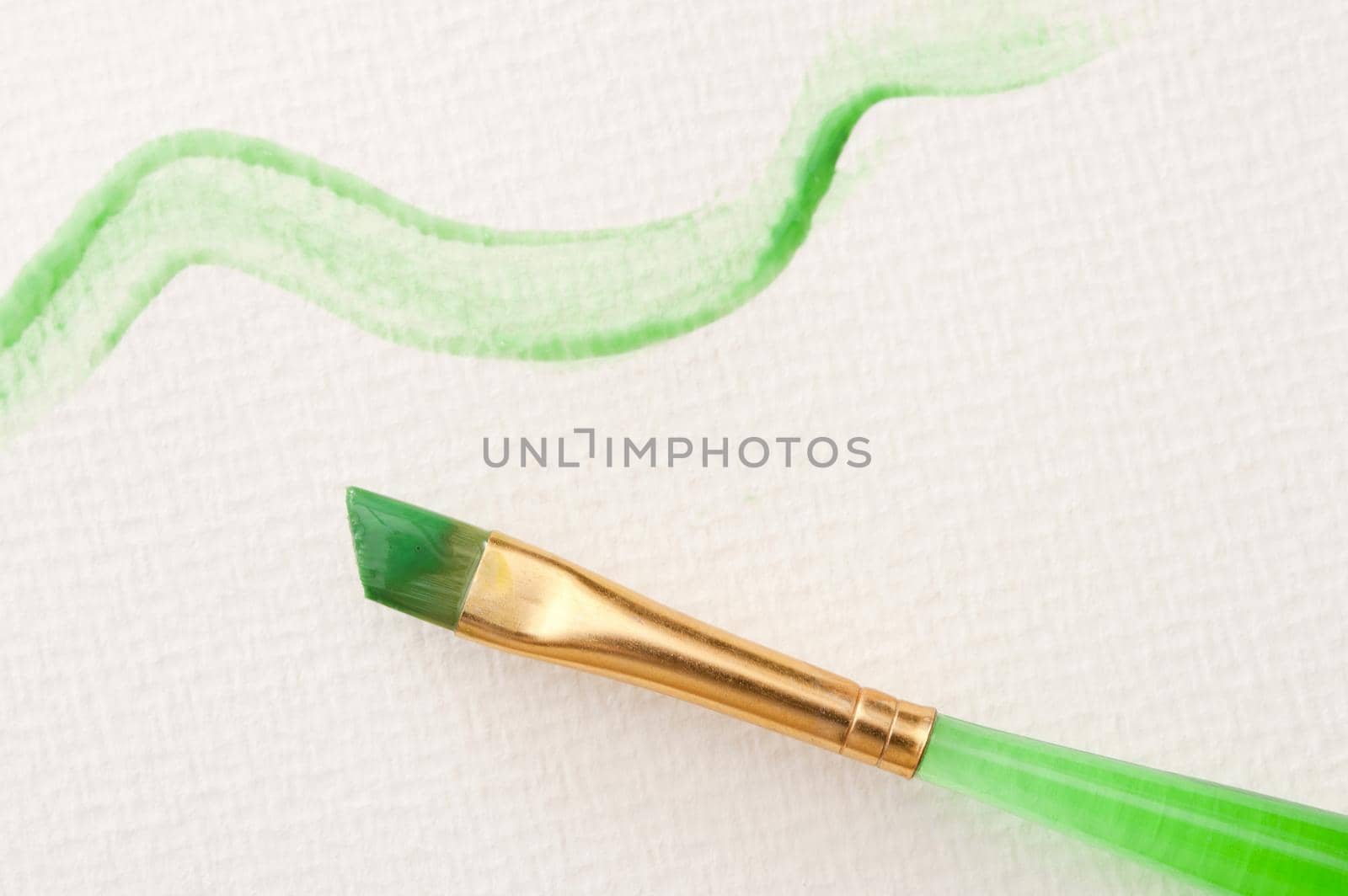 Squiggly green line made with watercolor and paintbrush over textured white canvas paper