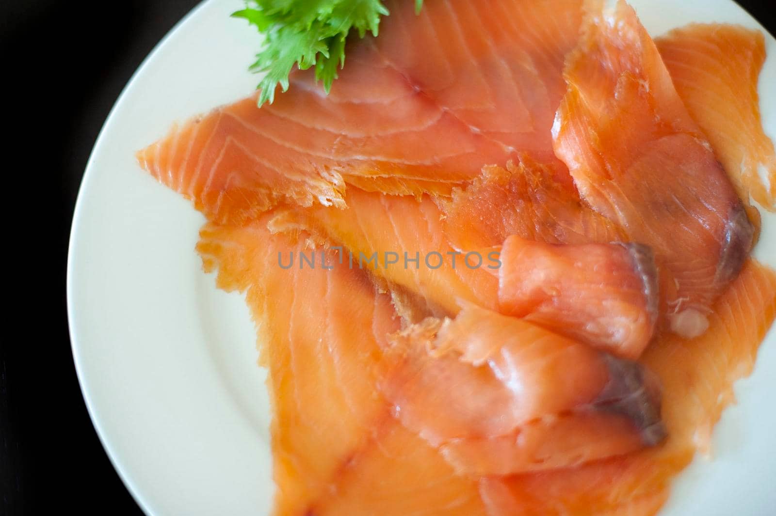Overhead view of a plate filled with gourmet smoked salmon slices garnished with parsley