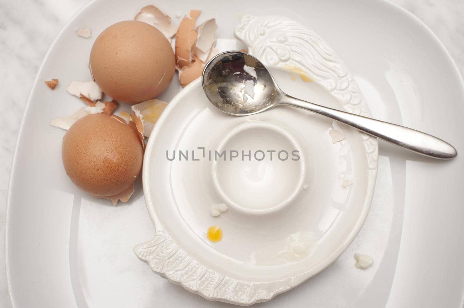 View from above of an empty egg cup with two overturned eggshells from two boiled eggs that have been consumed for breakfast