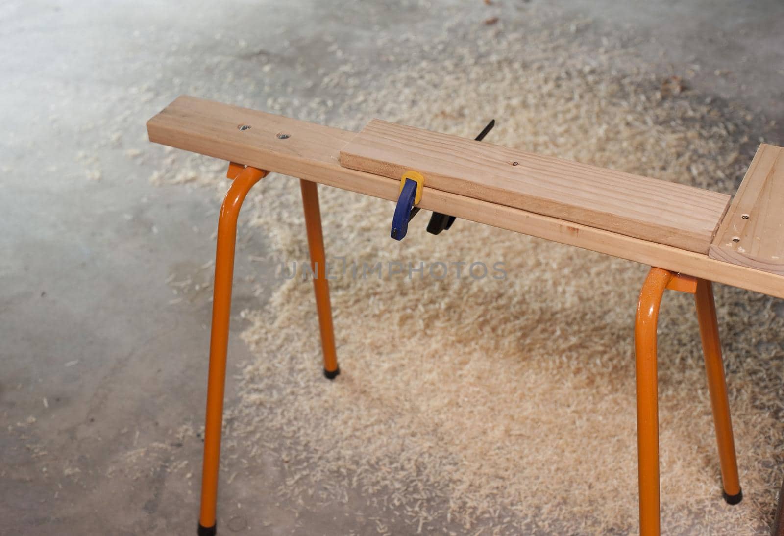 Carpenters horse or narrow work bench allowing easy access to planks of wood on both sides while clamped, surrounded by wood shavings