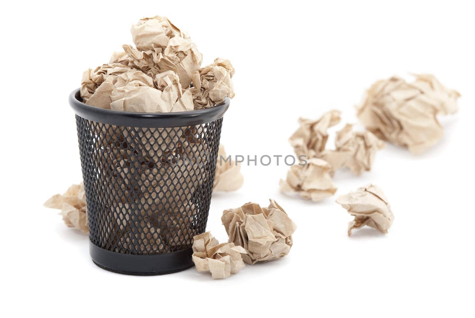 Discarding paper rubbish into a dedicated bin for recycling which is overflowing onto the floor