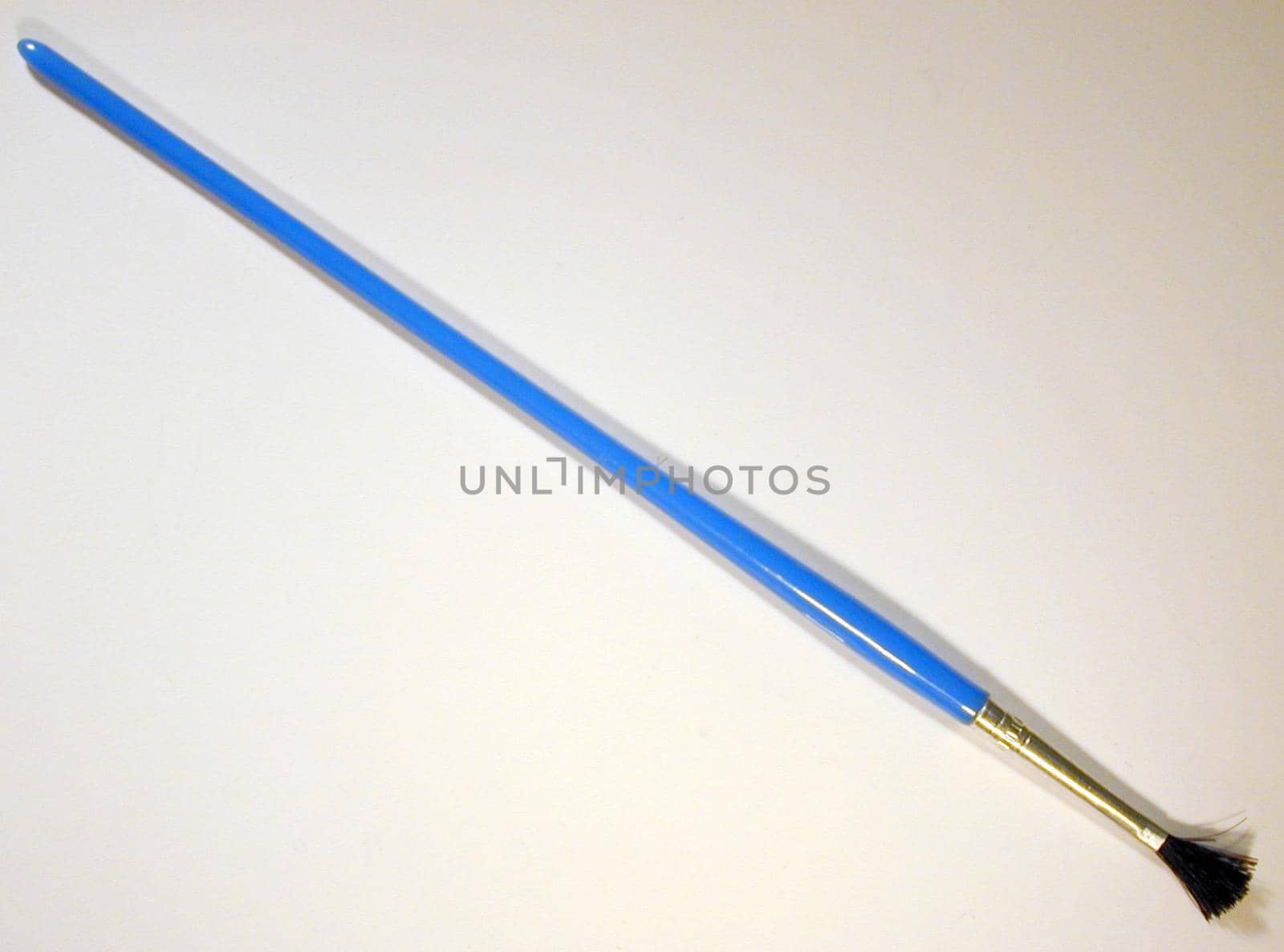 Single blue paintbrush with medium size tip on gray background with shadow