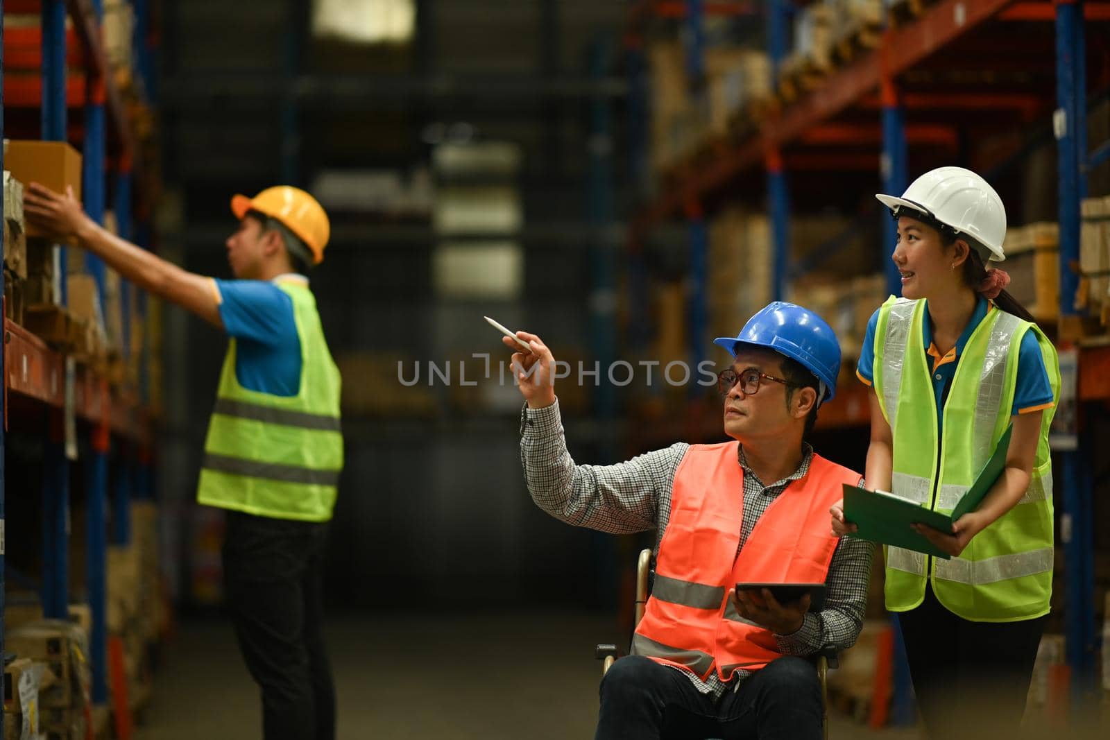 Storehouse employees workers in hardhats and and vests working together in warehouse. Logistics, and manufacture storehouse occupation concept by prathanchorruangsak