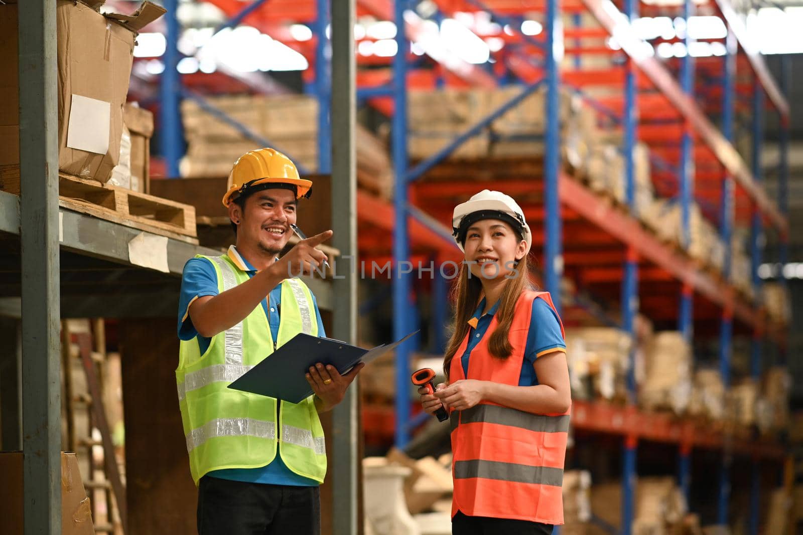 Storehouse employees workers in hardhats and and vests working together in warehouse. Logistics, and manufacture storehouse occupation concept.