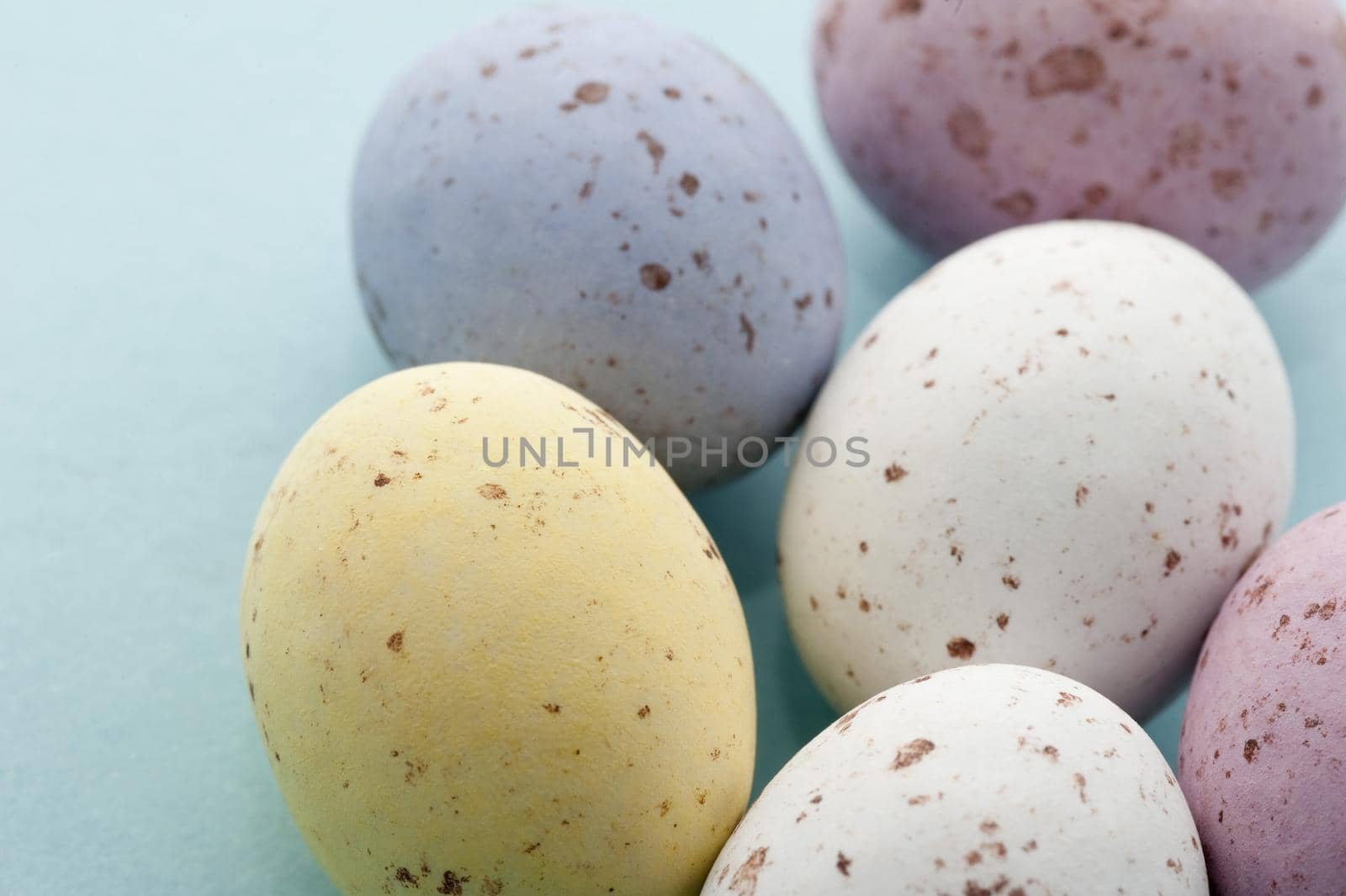 Closeup of five colourful speckled Easter Mini Eggs in sugared candy on a blue background