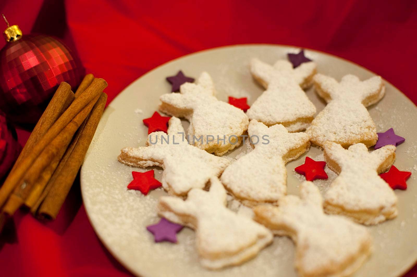 Fresh home baked angel Christmas cookies arranged with colourful stars on a plate on a festive Christmas table