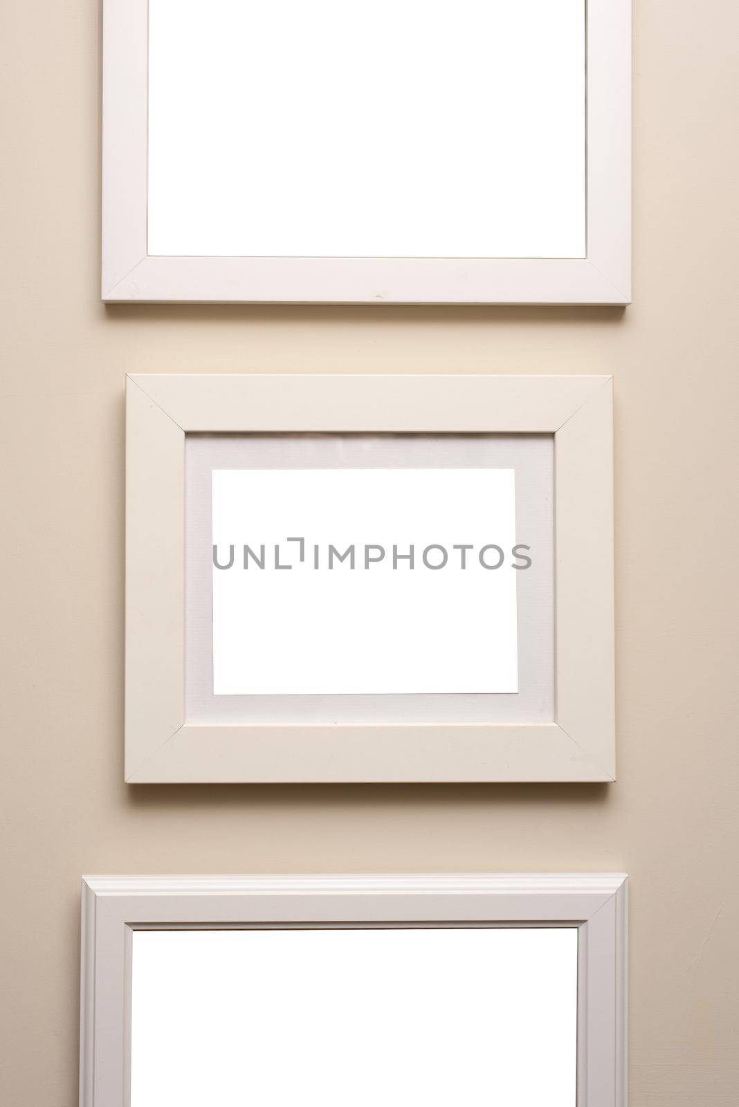 Assorted designs of neutral beige picture frames hanging on a matching colored wall in an art or decor themed background