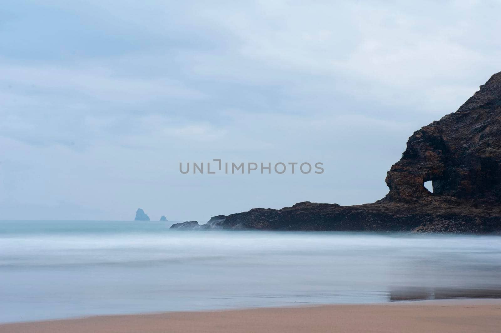 Coastline at Perran Beach, Perranporth, Cornwall with a calm sea on a misty overcast day
