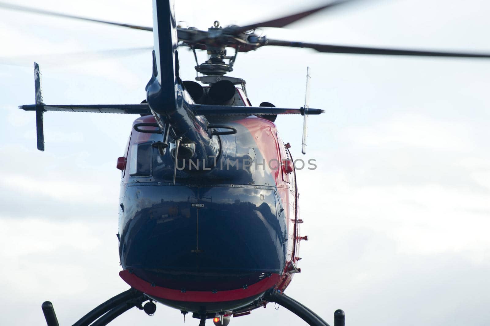 Helicopter taking off on a flight viewed from below the tail looking at the fuselage against a cloudy sky