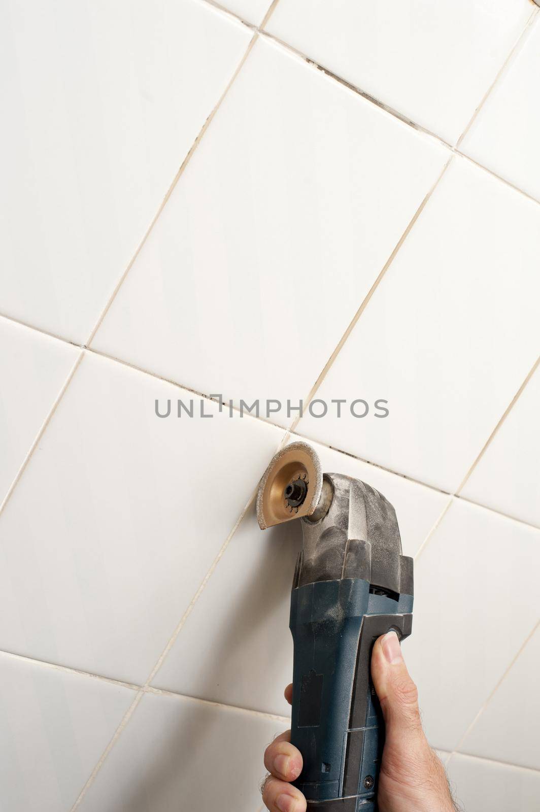 removing the grout from bathroom tiles with a diy renovator tool