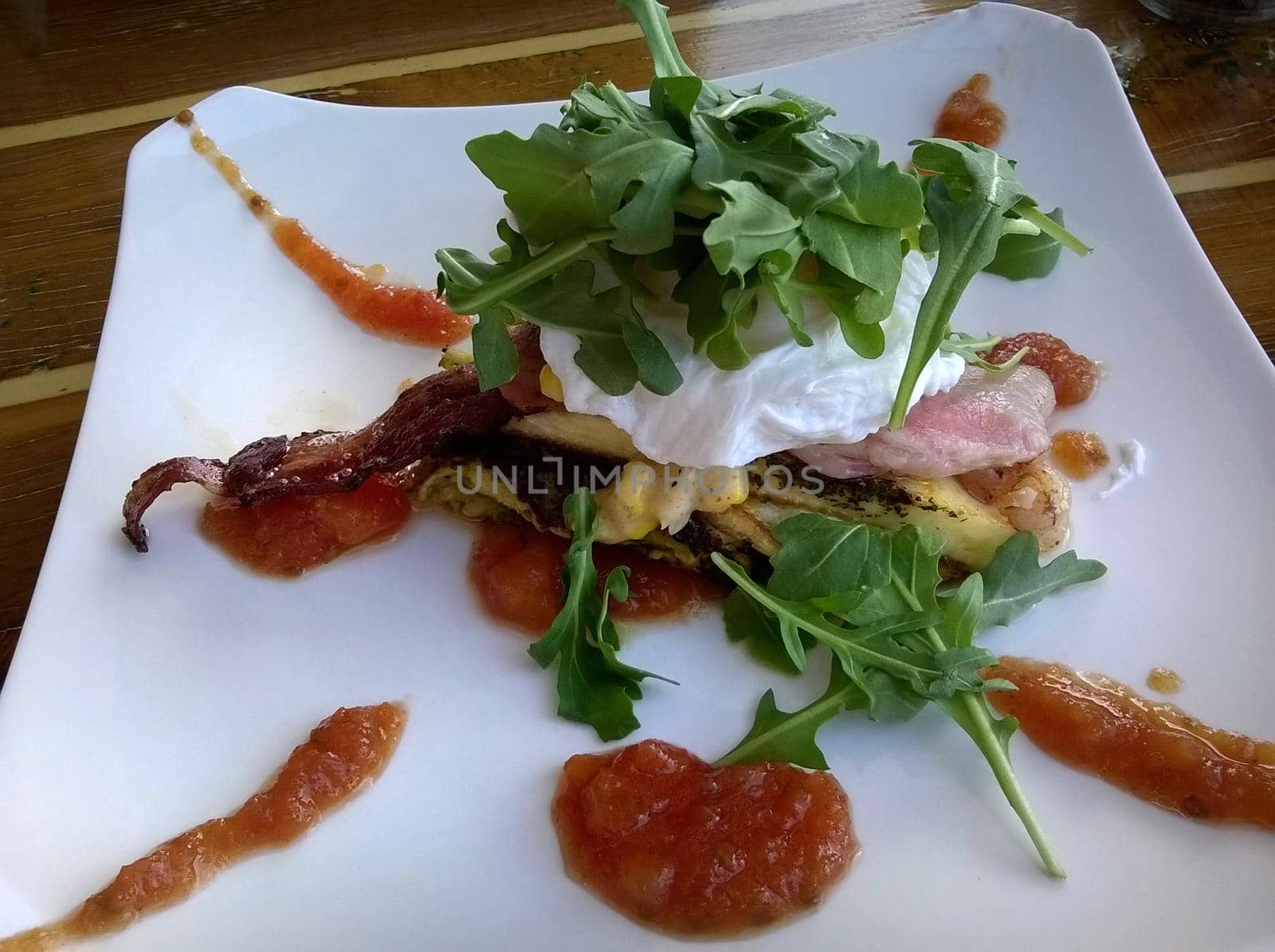 A gourmet restaurant breakfast dish of poached eggs with a healthy green garnish of rocket leaves.