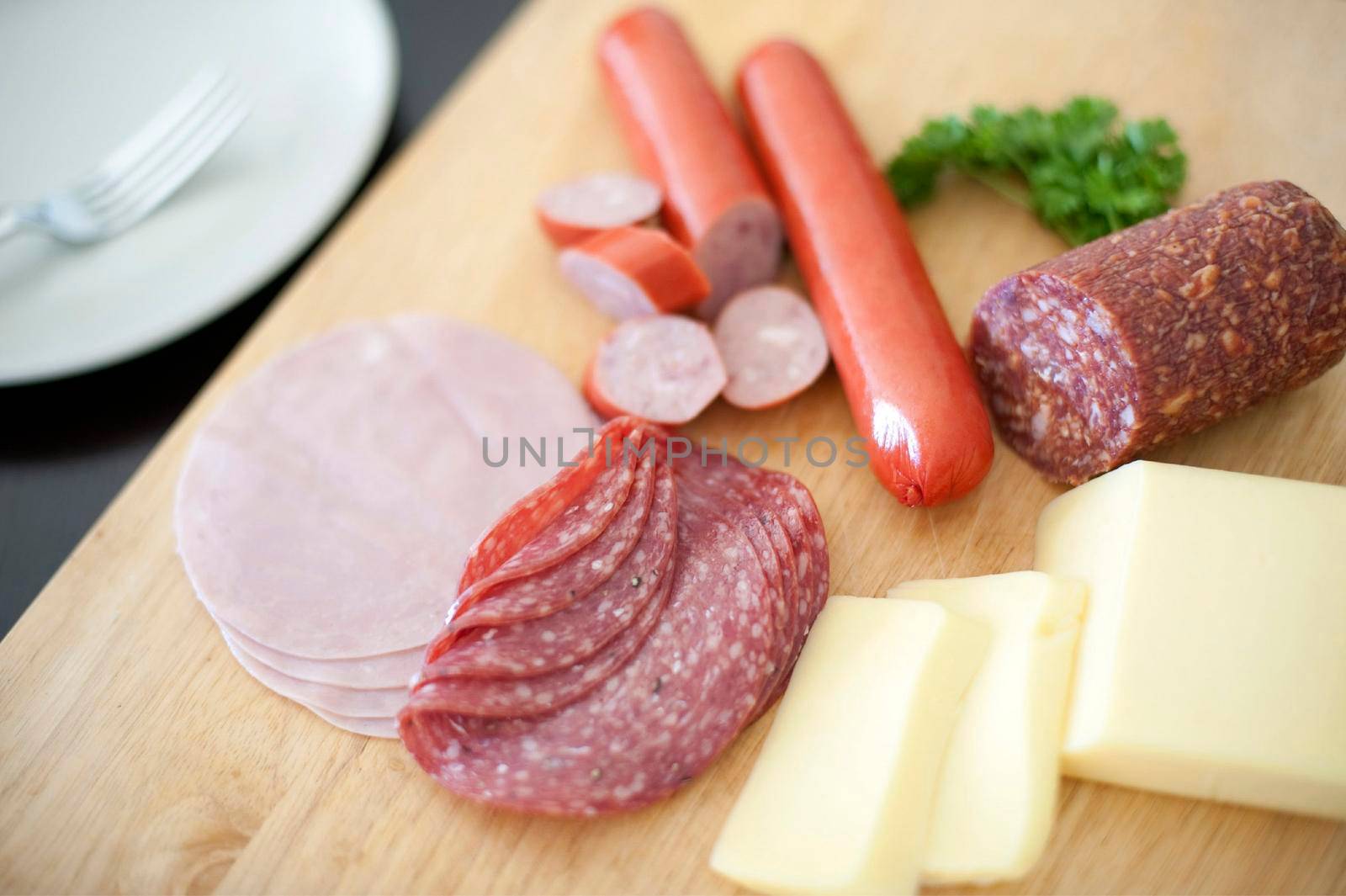 Nourishing German breakfast with sliced spicy salami or pepperoni sausage, cold ham and sliced cheese on a wooden chopping board
