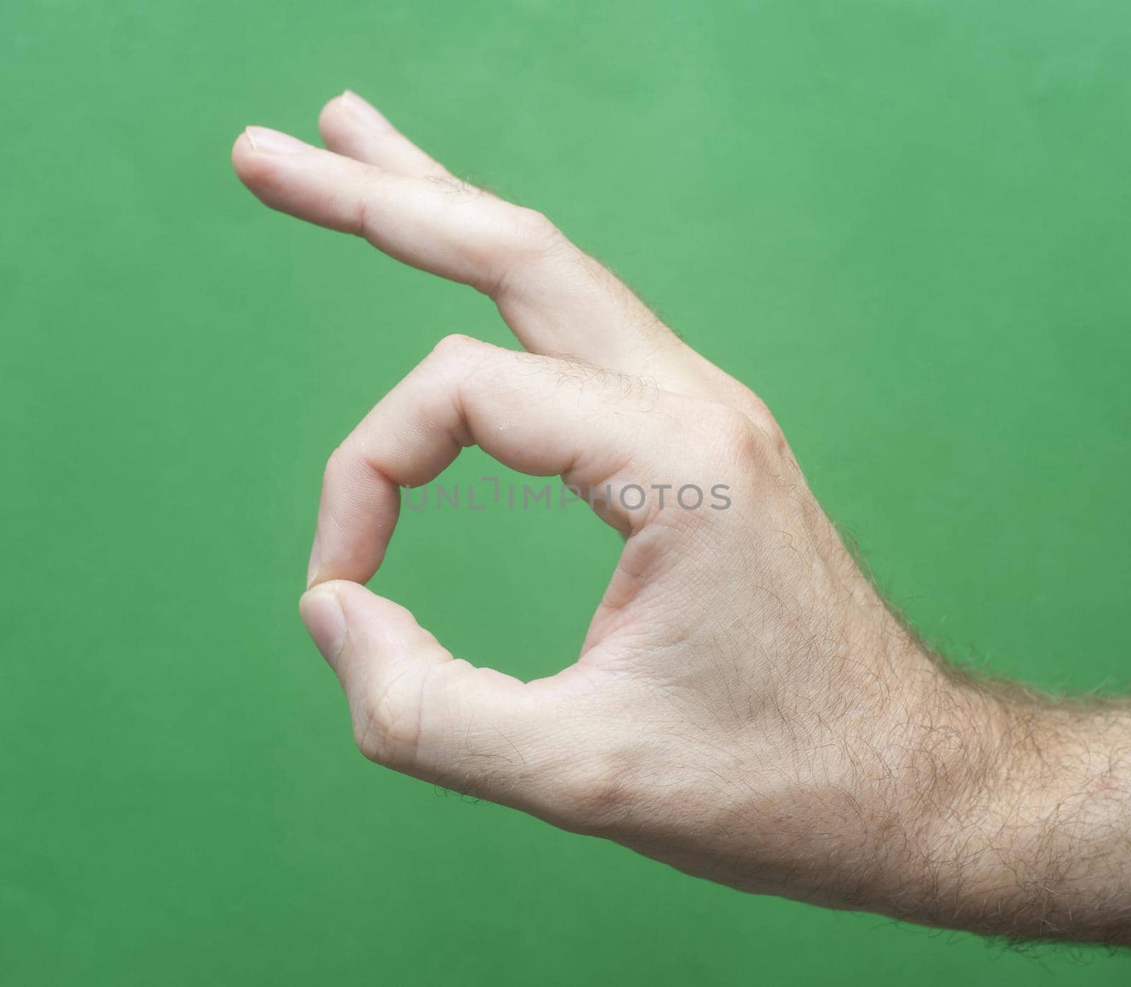 Close up Man Hand Showing Okay or Alright Sign Isolated on Green Background.