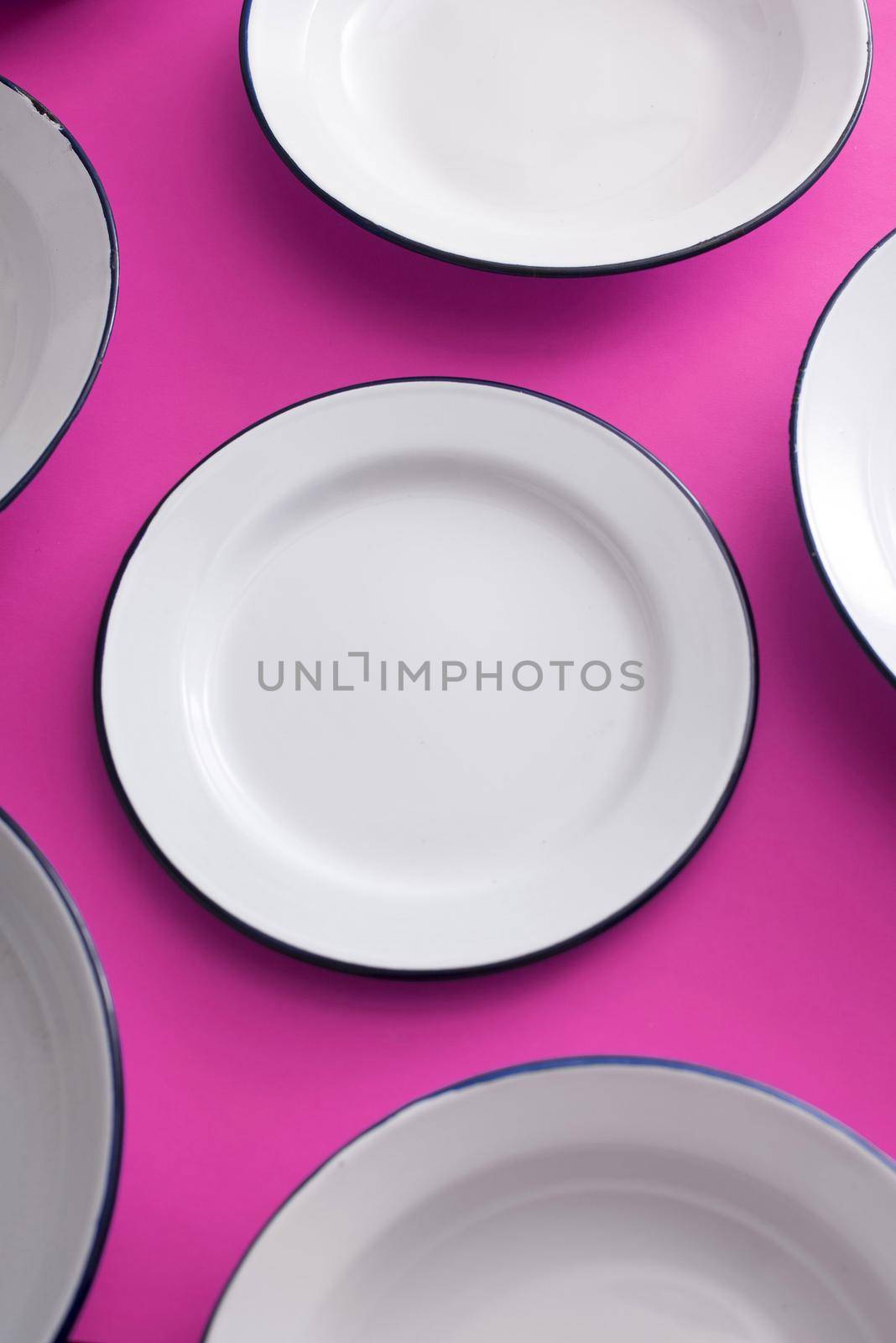 Clean white enamel plates spread out on a purple background in a full frame view for food themes