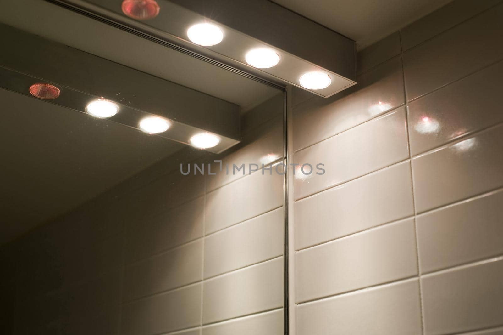 a row of halogen lights over a bathroom mirror