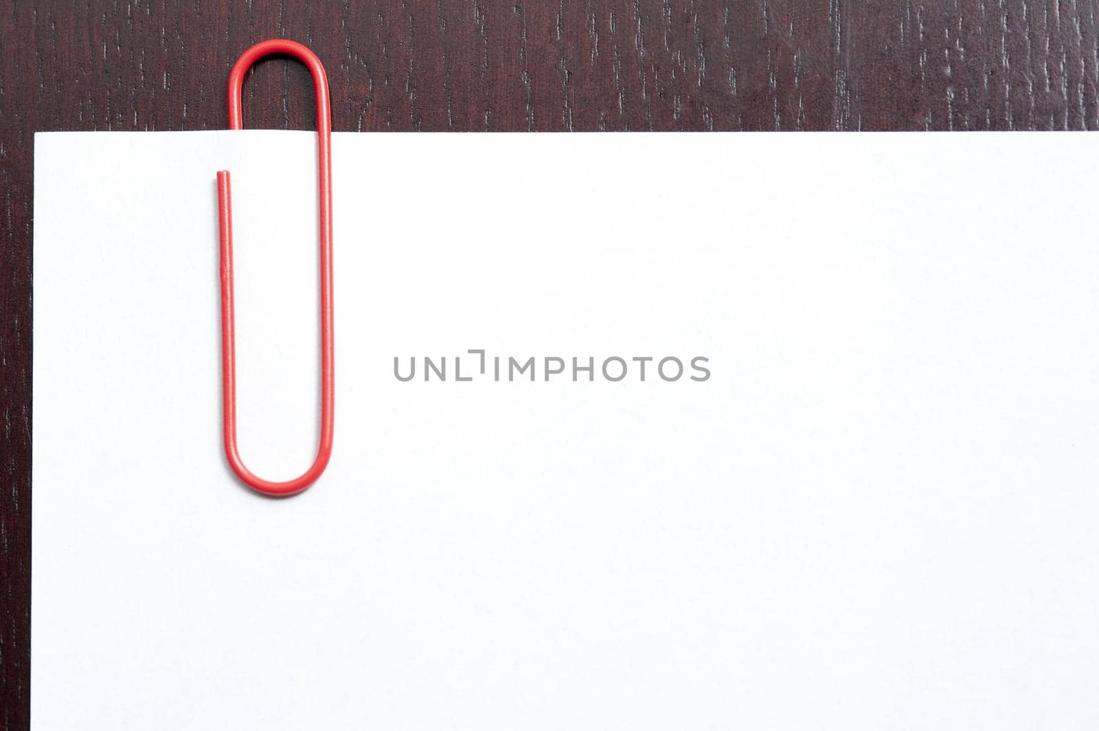 Red paperclip on blank paper with copy space