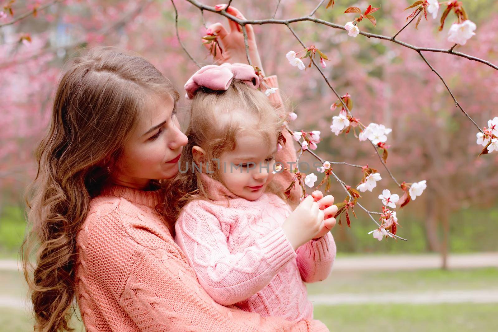mother and little girl in the park with blooming pink sakura by Zakharova