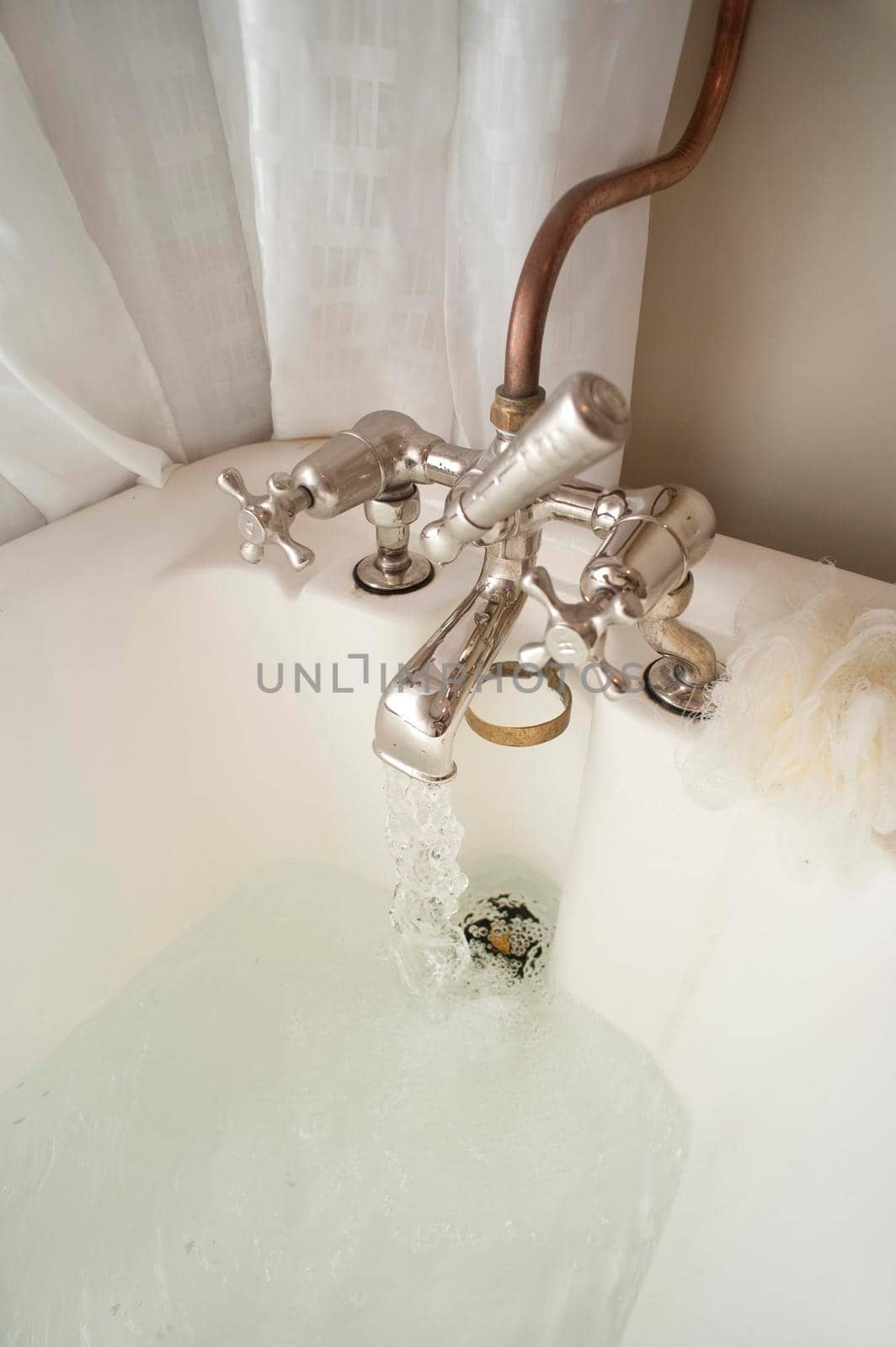 Retro bathroom tap mounted on a bathtub with inviting hot water filling the bath