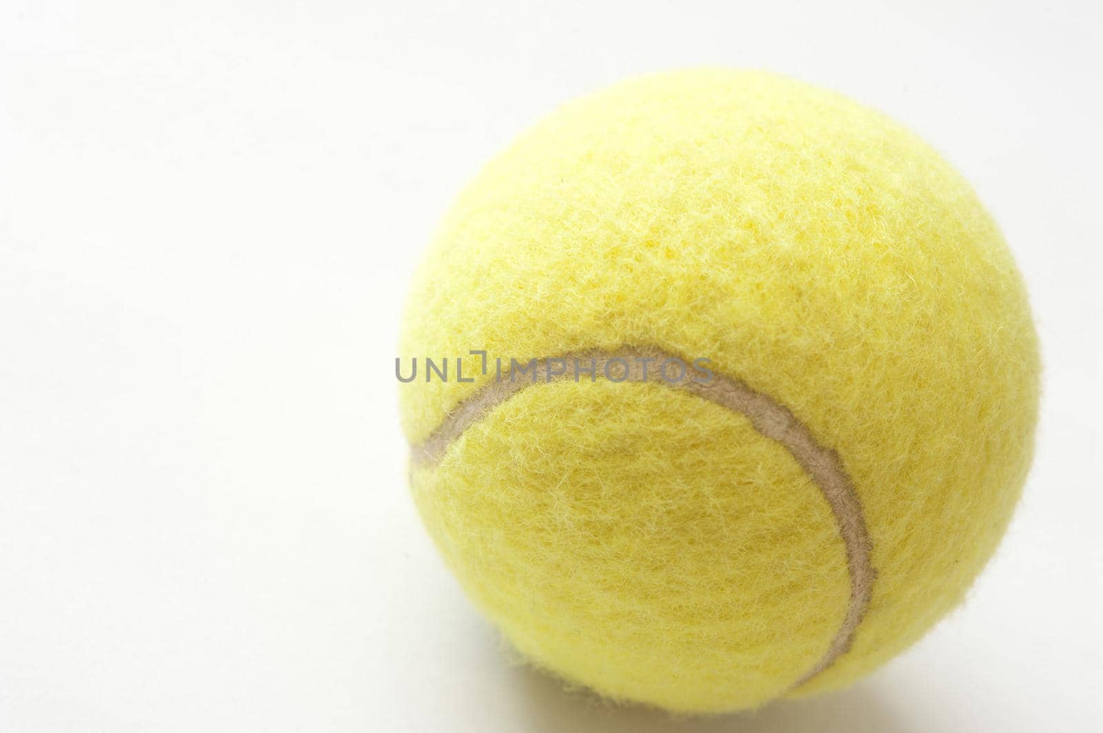 Close up of a yellow tennis ball on white with copyspace in a sport and fitness concept