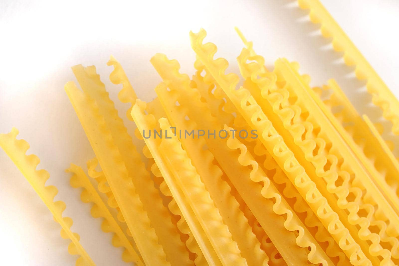 Dried reginette pasta with its distinctive frilly wavy edges for use in traditional Italian cuisine, overhead view on white