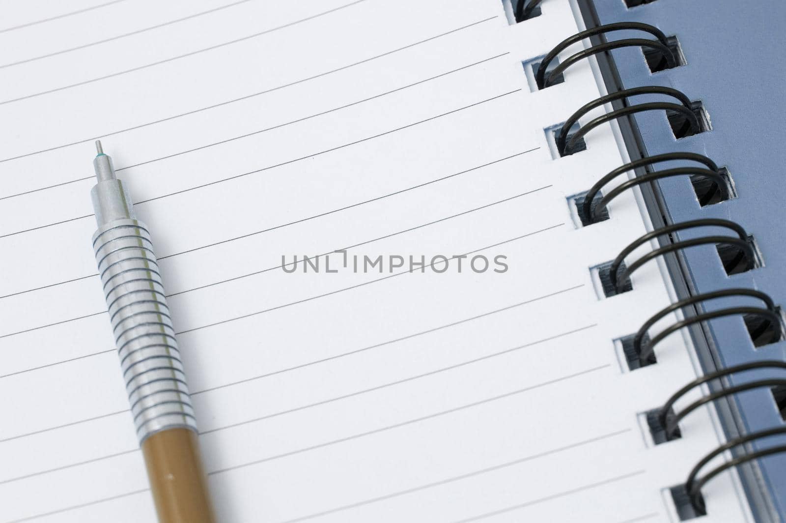 Mechanical pencil lying on the lined blank page of a ringbound notepad