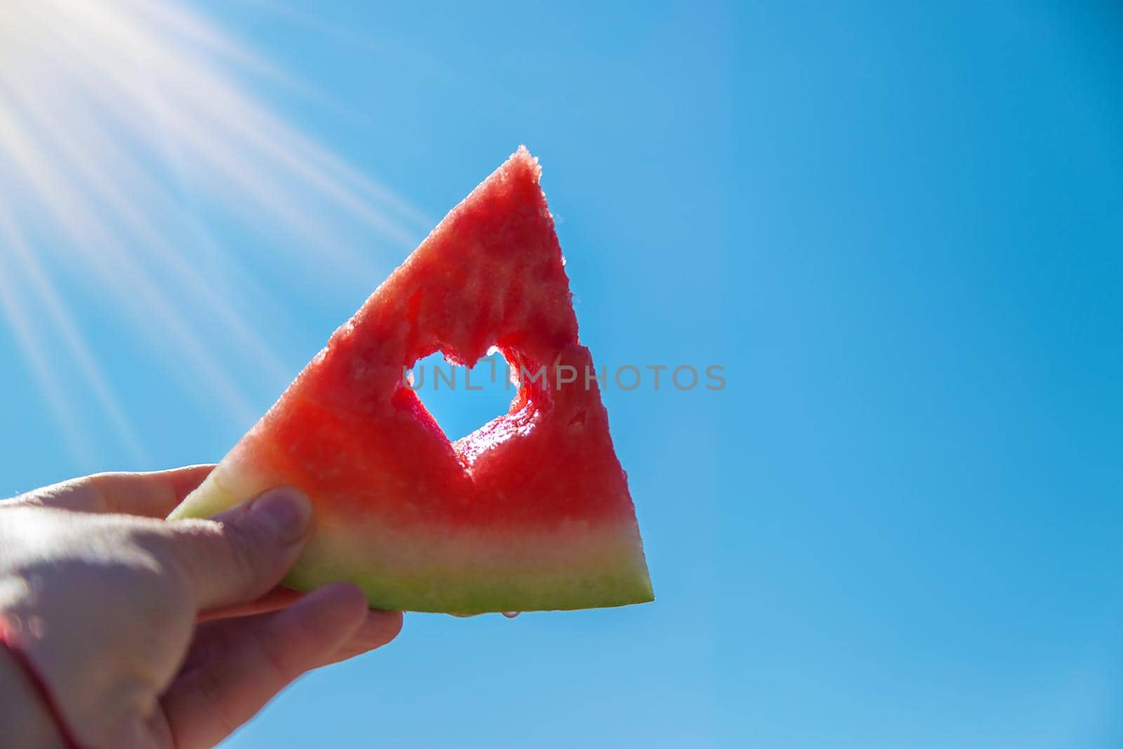 Watermelon in hand against the sky. Selective focus. Kid.