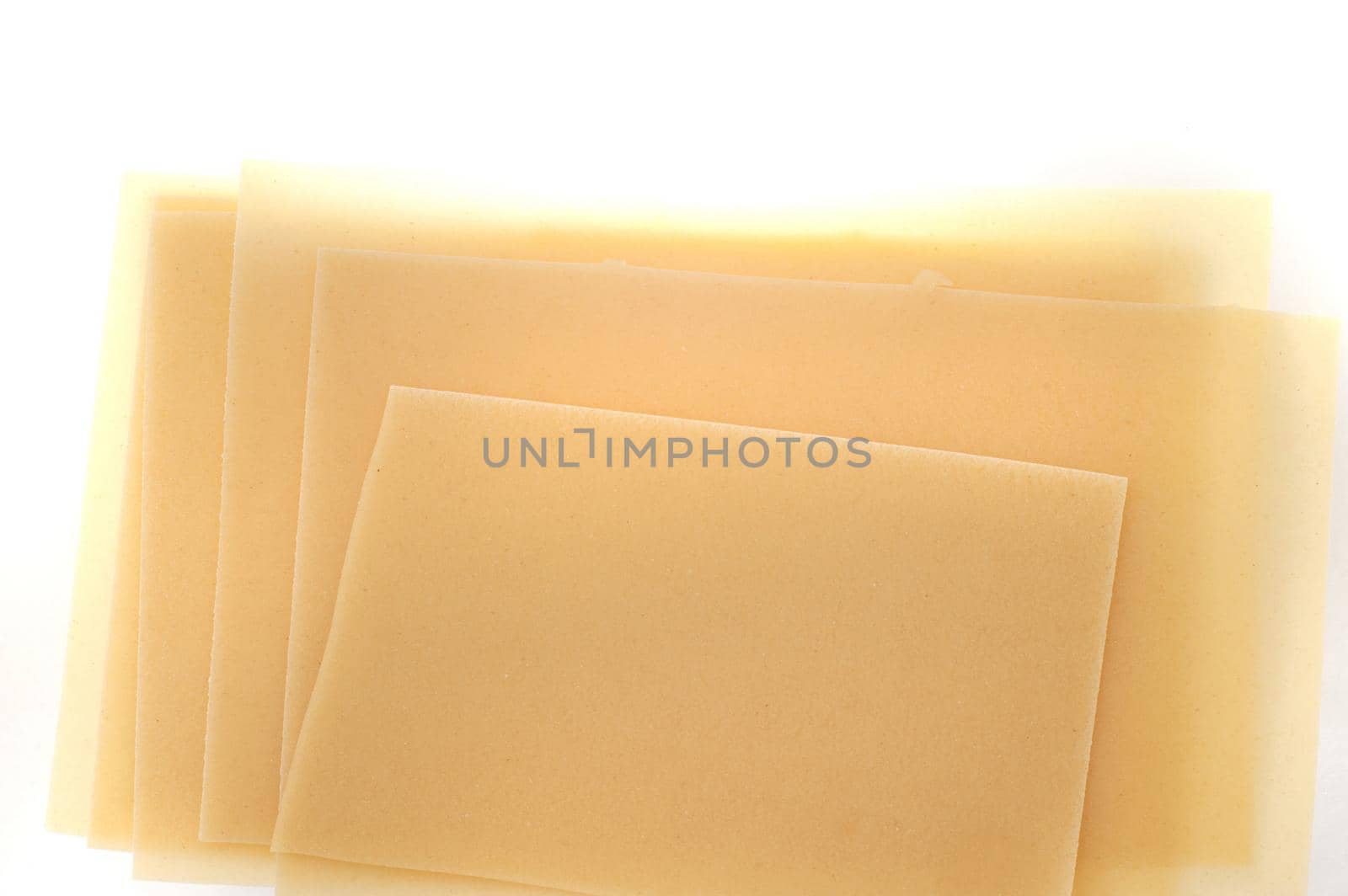 Dried uncooked traditional Italian lasagne sheets made from durum wheat dough on a white background